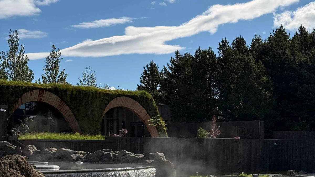 Turf-roofed timber bath house and steaming pool at Laugarás Lagoon on the Golden Circle in South Iceland